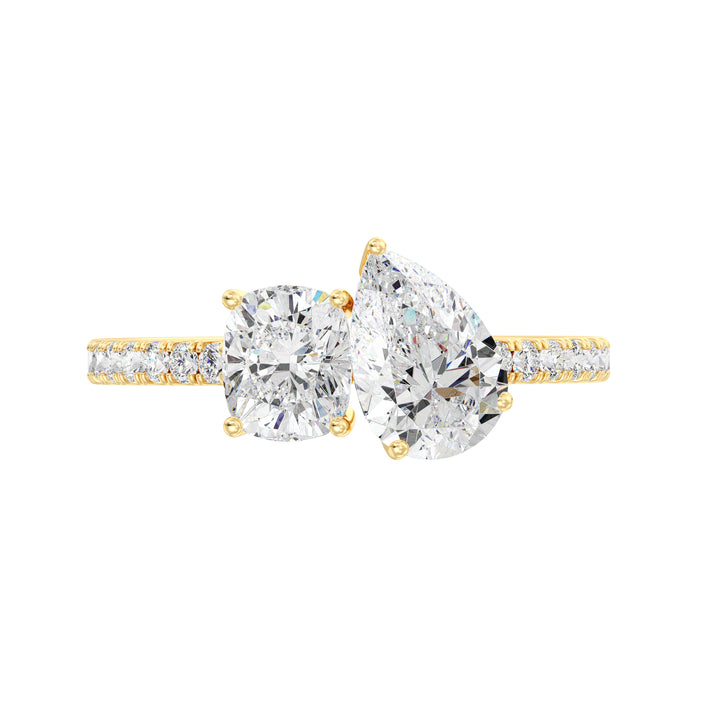 A stunning Pear & Cushion Two-Stone Lab-Grown Diamond 'Toi et Moi' Ring in 18K Yellow Gold. Featuring a 1.00ct Pear-cut diamond and 1.00ct Cushion-cut diamond, set side by side in a classic prong setting. The band is adorned with 16 Round-Cut Lab-Grown Diamonds (0.24ct total), adding extra sparkle. The warm yellow gold enhances the brilliance of the diamonds, creating a timeless and elegant look.