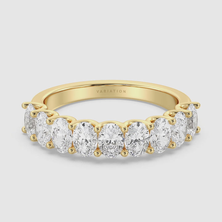 A close-up video of the Lab-Grown Diamond Oval Scallop Half Eternity Wedding Ring in 18K Yellow Gold. The video showcases the ring's intricate design, highlighting the 9 oval-cut diamonds set in a low-profile shared prong setting. The camera rotates around the ring, emphasizing the brilliance of the EF/VS lab-grown diamonds and the rich, warm tone of the yellow gold band.