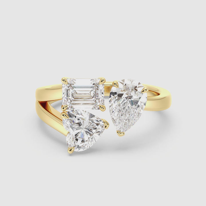 Close-up video of a Three-Stone Toi et Moi Lab-Grown Diamond Ring in 18K Yellow Gold, featuring a 1.00ct Heart, 1.00ct Pear, and 1.00ct Emerald-cut diamond in a classic prong setting. The warm yellow gold band beautifully complements the brilliance of the EF/VS clarity lab-grown diamonds, showcasing their exceptional sparkle from multiple angles