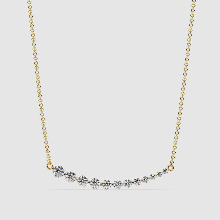 Elegant asymmetric smile necklace in 18K yellow gold featuring 12 round-cut lab-grown diamonds totaling 0.80 carats, hand-set in a graduated prong setting along a curved pendant.