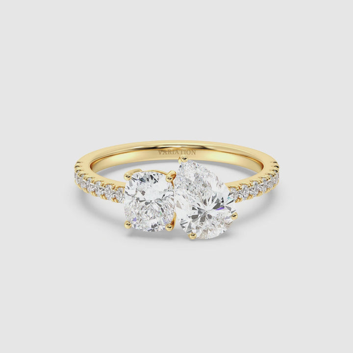 Close-up video of a stunning Pear & Cushion Two-Stone Lab-Grown Diamond 'Toi et Moi' Ring in 18K Yellow Gold. The 1.00ct Pear-cut diamond and 1.00ct Cushion-cut diamond sparkle brilliantly in a classic prong setting, symbolizing the union of two souls. The band, adorned with 16 Round-Cut Lab-Grown Diamonds (0.24ct total), shimmers elegantly. The warm yellow gold setting enhances the brilliance of the diamonds, creating a timeless and romantic look.