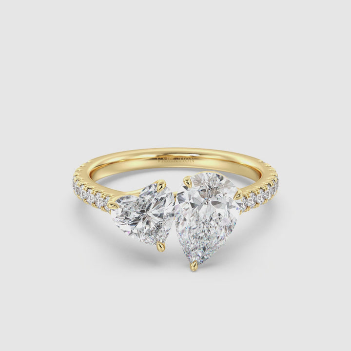 18K Yellow Gold Toi et Moi Engagement Ring featuring a 1.50ct Pear-Cut and 1.00ct Heart-Shaped Lab-Grown Diamond in a classic prong setting, accented with a pavé band of 20 round-cut diamonds (0.36ct total). A timeless two-stone ring symbolizing love and unity, shimmering elegantly in warm yellow gold