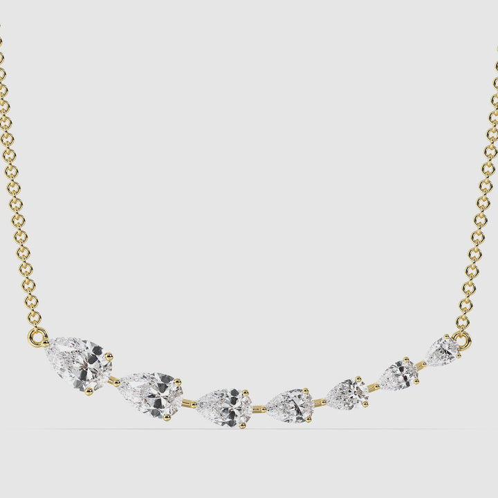 Graduated pear-cut lab-grown diamond necklace in 18K yellow gold featuring seven EF/VS diamonds totaling 3.07 carats, set in a delicate asymmetric smile curve design with a prong setting
