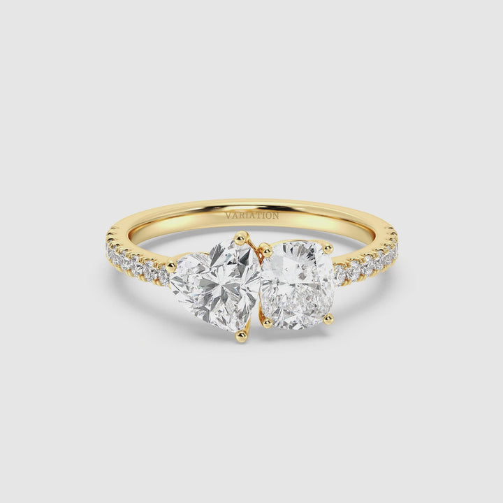 Close-up video of a stunning Heart & Cushion Two-Stone Lab-Grown Diamond 'Toi et Moi' Ring in 18K Yellow Gold. The ring features a 1.00ct heart-cut and a 1.00ct cushion-cut lab-grown diamond, both EF/VS clarity, set in a classic prong setting. The sleek yellow gold band is adorned with 16 round-cut lab-grown diamonds (0.24ct), adding extra brilliance. The video showcases the ring’s sparkle, elegant craftsmanship, and luxurious warm gold hue from multiple angles.