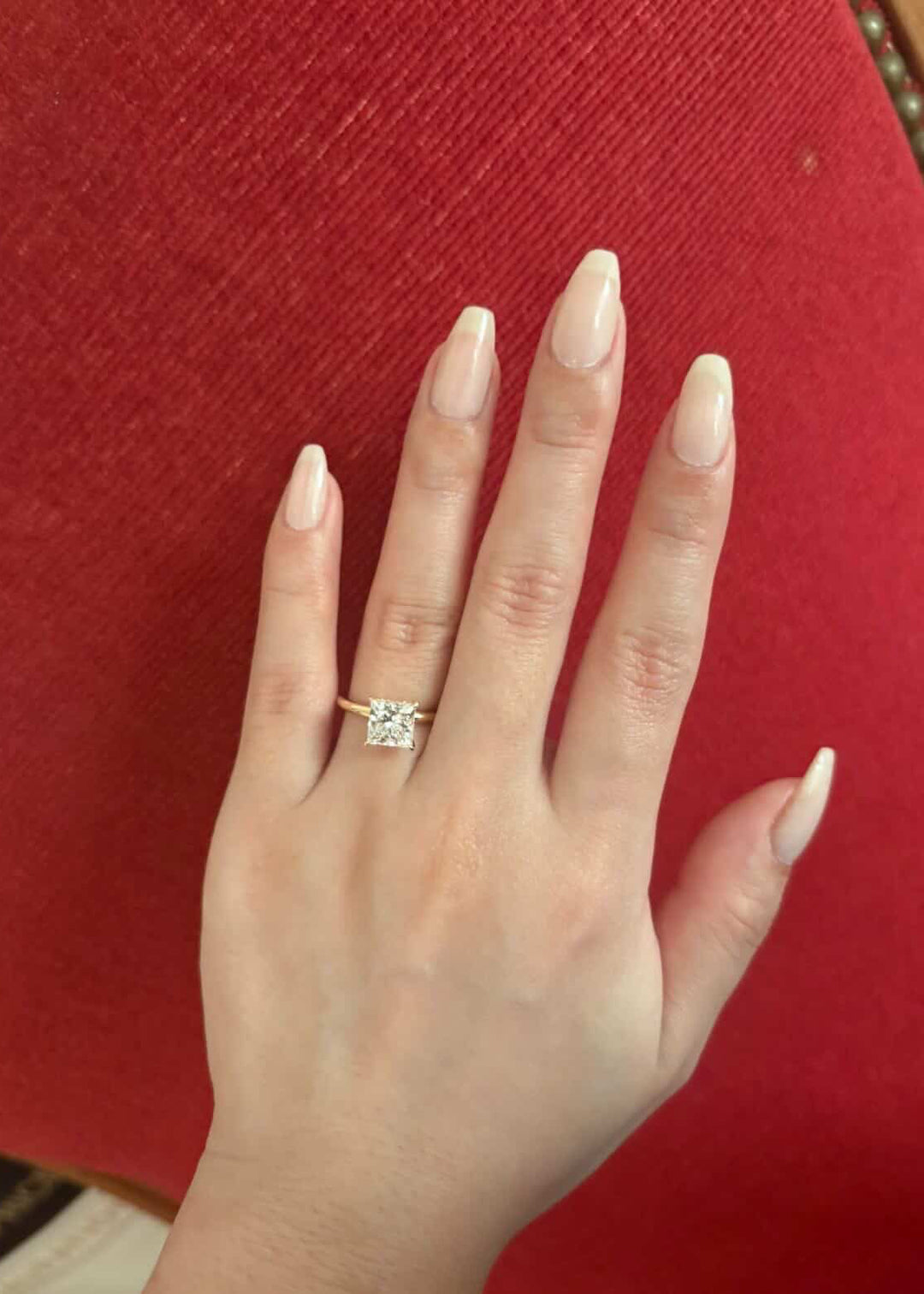 Woman wearing 1.5 carat princess cut lab grown diamond ring with hidden halo in 18K yellow gold