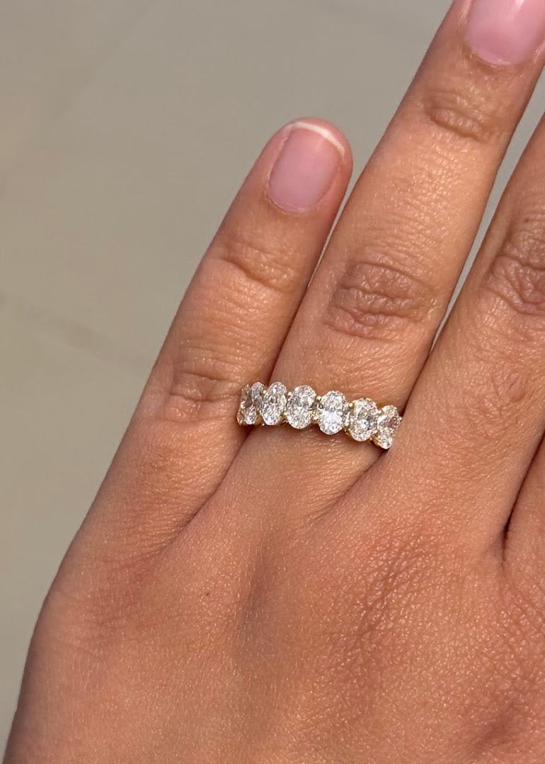 Woman wearing 7 stone oval cut lab grown diamond eternity band 0.30 carat each in 18K yellow gold