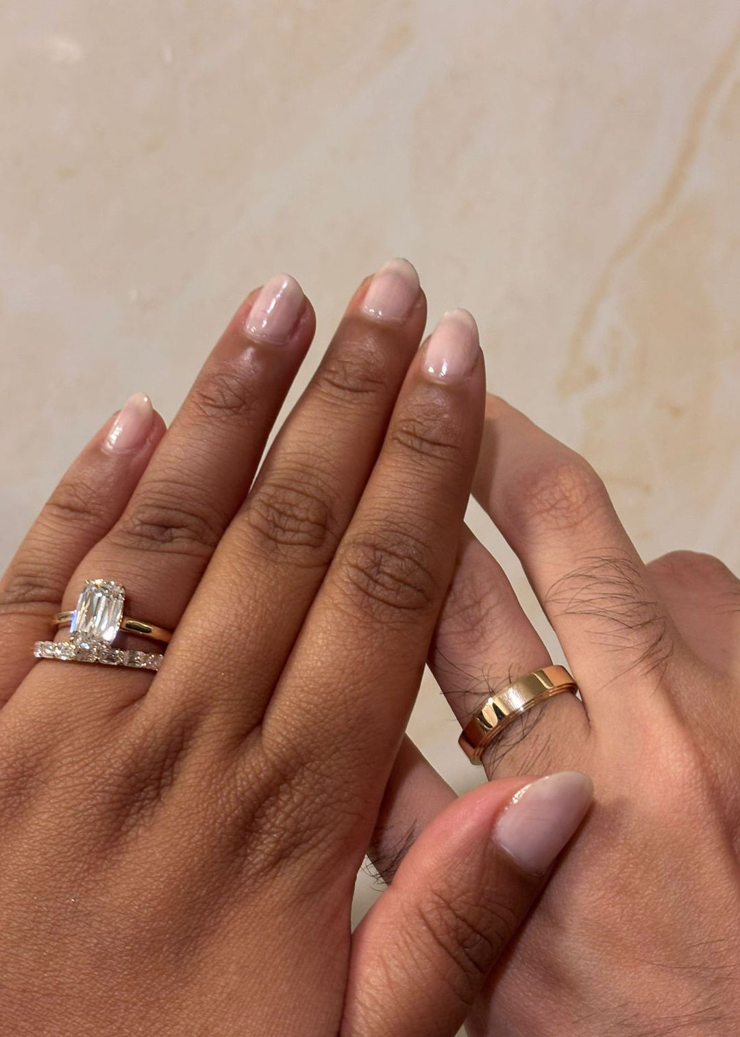 Couple hands with woman wearing Ashoka cut lab grown diamond solitaire ring and man wearing 18K yellow gold band