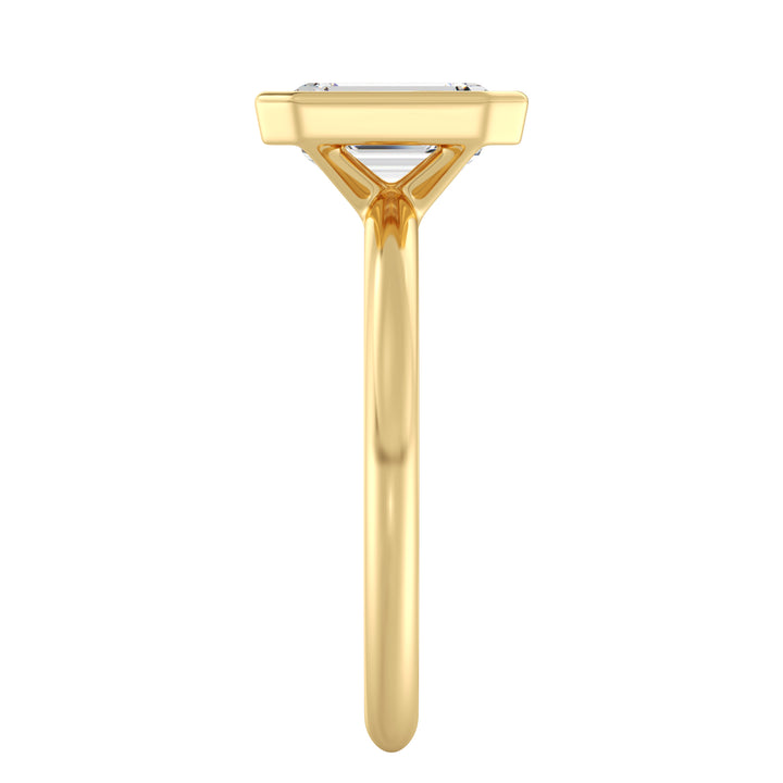 Close-up view of an emerald cut lab grown diamond bezel solitaire ring in 18K yellow gold featuring an IGI certified diamond with step-cut facets and a sleek bezel setting.