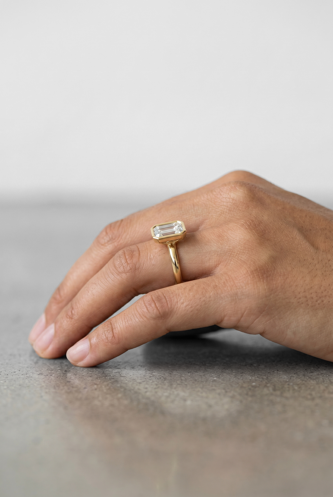 IGI certified emerald cut lab grown diamond bezel solitaire ring in BIS hallmarked 18K yellow gold.