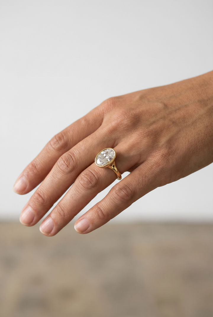 Elegant oval cut lab grown diamond bezel engagement ring crafted in 18K yellow gold with a sleek contemporary design.