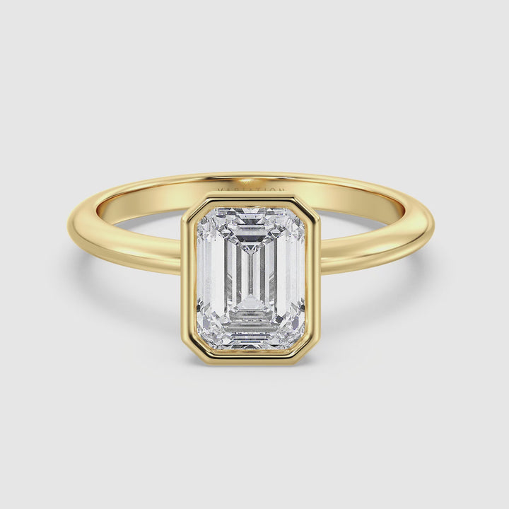 Close-up video of the Emerald Cut Lab-Grown Diamond Bezel-Set Solitaire Ring in 18K Yellow Gold. The video captures the ring’s radiant emerald cut diamond as it sparkles within a sleek bezel setting, emphasizing the rich, warm hue of the yellow gold band. The diamond’s exceptional brilliance is highlighted from various angles, showcasing the ring's elegant design and timeless appeal