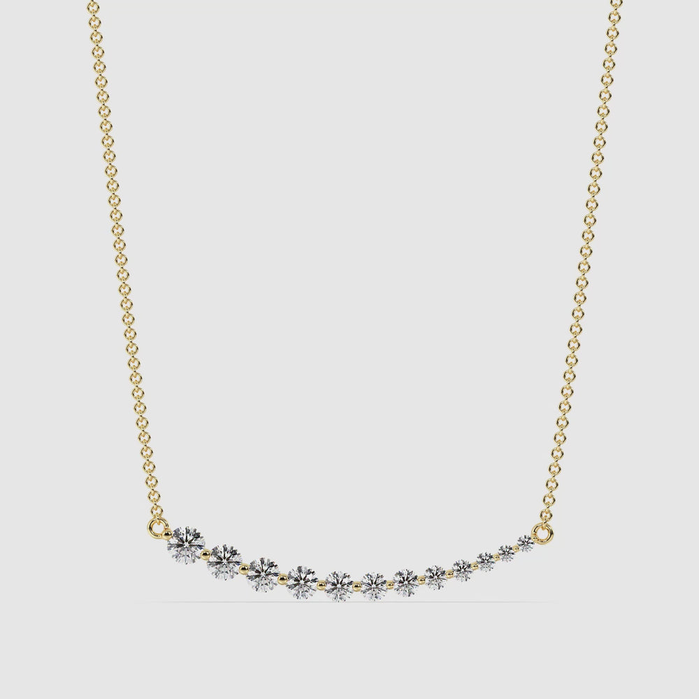 Elegant asymmetric smile necklace in 18K yellow gold featuring 12 round-cut lab-grown diamonds totaling 0.80 carats, hand-set in a graduated prong setting along a curved pendant.