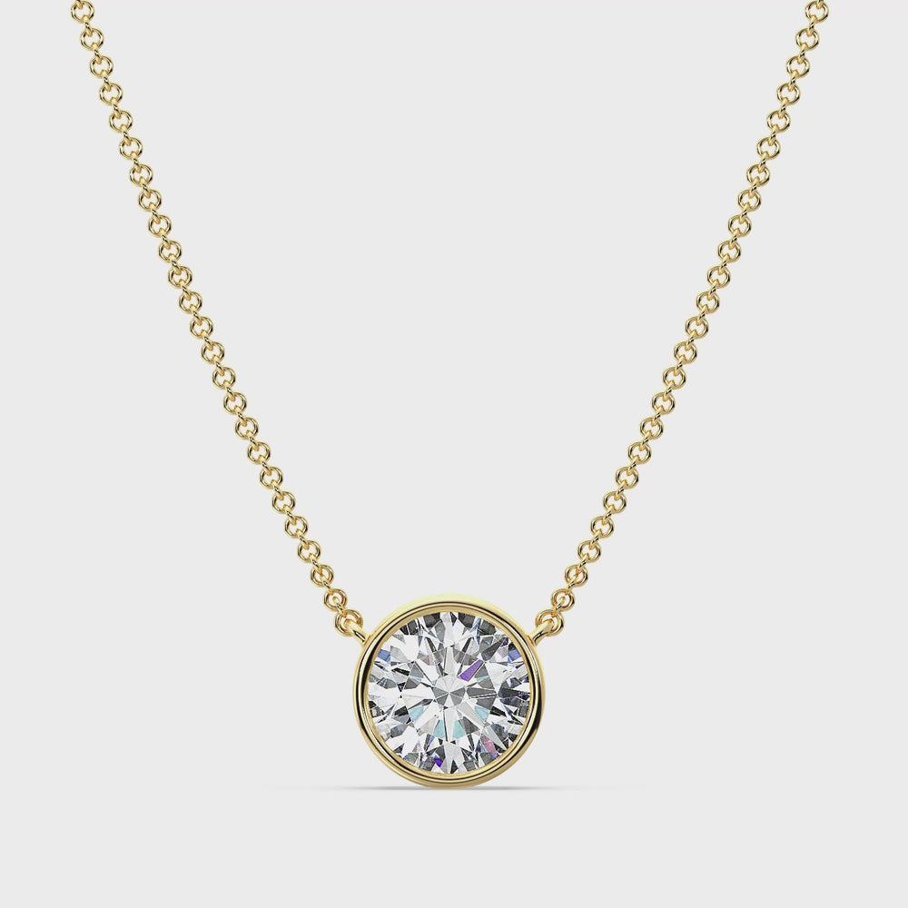 Close-up video showcasing a 2 Carat Bezel-Set Round Lab-Grown Diamond Solitaire Pendant Necklace in 18K Yellow Gold. The IGI-certified E/VS diamond sparkles brilliantly at the center, set securely in a sleek bezel setting, highlighting the elegant chain and warm yellow gold tone. Perfect for weddings or everyday luxury