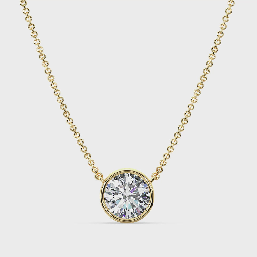 Close-up video showcasing a 2 Carat Bezel-Set Round Lab-Grown Diamond Solitaire Pendant Necklace in 18K Yellow Gold. The IGI-certified E/VS diamond sparkles brilliantly at the center, set securely in a sleek bezel setting, highlighting the elegant chain and warm yellow gold tone. Perfect for weddings or everyday luxury