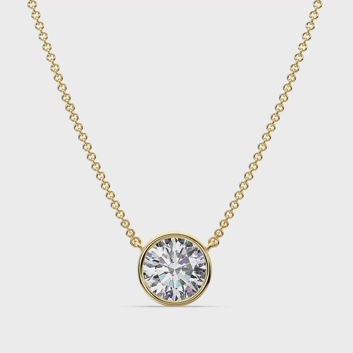 Close-up video showcasing a 2 Carat Bezel-Set Round Lab-Grown Diamond Solitaire Pendant Necklace in 18K Yellow Gold. The IGI-certified E/VS diamond sparkles brilliantly at the center, set securely in a sleek bezel setting, highlighting the elegant chain and warm yellow gold tone. Perfect for weddings or everyday luxury